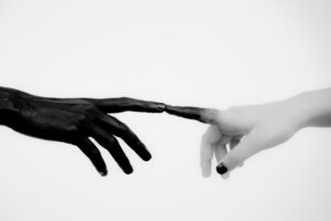 Black painted hand touching a clean hand