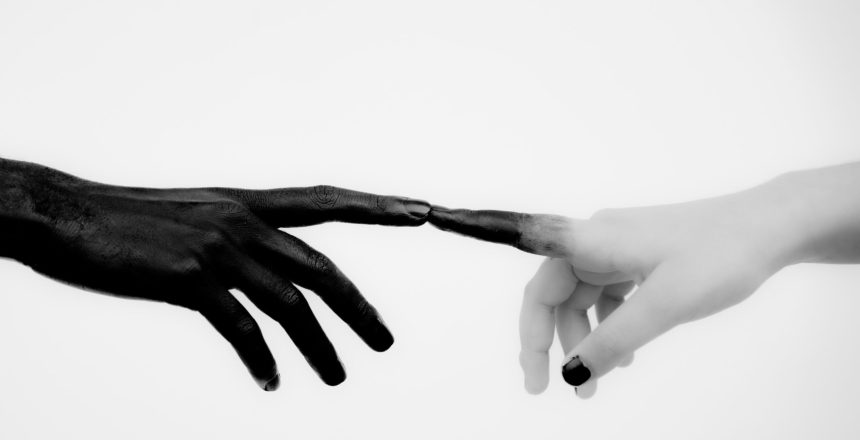 Black painted hand touching a clean hand